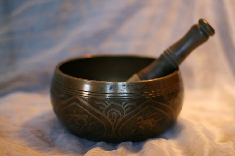 A brass singing bowl with its wooden striker